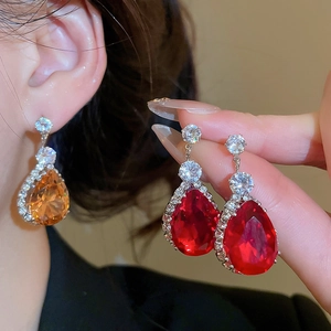 Close-up of red and orange teardrop earrings with halo crystals in vintage style