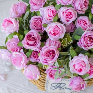 Close-up of artificial pink roses in a woven basket with Flowers label decor