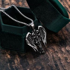 Detailed view of a silver gothic winged sword pendant in a green velvet jewelry box