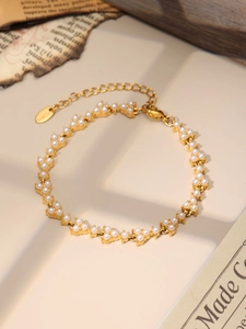 Detail of clover pearl bracelet in gold stainless steel on vintage newspaper background