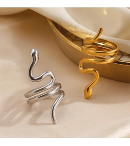 Détails de bagues serpent dorées et argentées posées sur un élégant tissu en soie beige