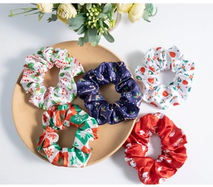 Detailed close-up of festive satin hair scrunchies with various Christmas patterns and prints