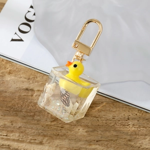 Detail of creative 3D yellow duckling resin cube keychain with shells and gold buckle