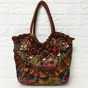 Detailed view of a brown satin handbag with 3D fabric roses and leaf patterns