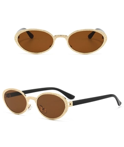 Macro detail of oval sunglasses with gold hammered texture frame and brown lenses