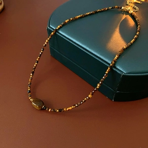 Macro shot of tiger eye beaded necklace with a central barrel stone and golden clasp