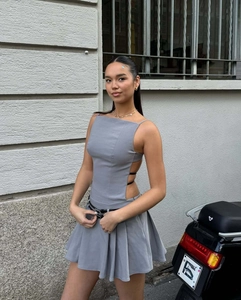 Détail de la robe grise plissée avec découpes latérales et accents de ceinture noire