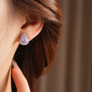 Close-up of elegant purple pear-shaped earrings with sparkling cubic zirconia on model
