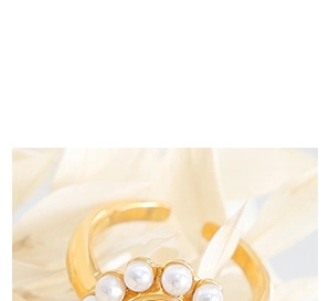 Macro d'une bague plaquée or 18 carats avec cinq perles blanches sur fond floral