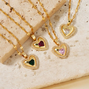 Elegant gold heart pendant necklace set with colorful zircon stones on stone background