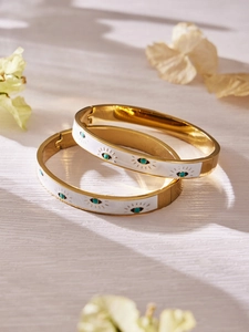Detailed close-up of golden stainless steel evil eye bangles with white enamel and turquoise