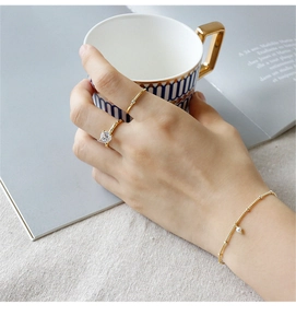 Detailed view of gold pearl bracelet and crystal rings on a lifestyle coffee scene