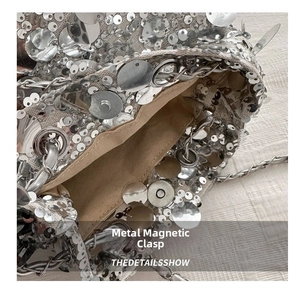 Detailed close-up of the silver sequin bag showing the metal magnetic buckle and lining