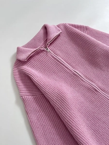 Dettaglio maglione rosa a maglia grossa con trama a coste verticali e zip metallica