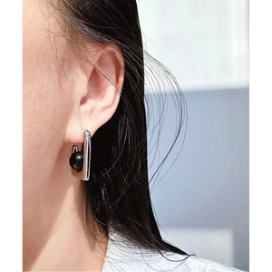 Minimalist silver U-shaped earrings with black agate round beads shown on model