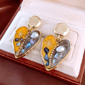 Close-up of golden heart earrings with pearls and glitter inside a velvet jewelry box
