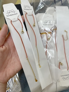 Detail showing the red cord and stainless steel lobster clasp on a gold-plated bracelet