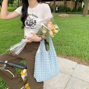 Detail of light blue bubble texture tote bag styled with white t-shirt and casual pants