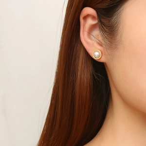 Elegant gold titanium steel pearl earrings worn by a model in a minimalist style