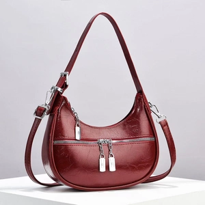 Chic burgundy faux leather crossbody bag with silver buckles and a crescent silhouette