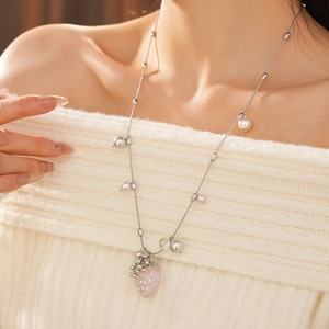 Detail of strawberry pendant necklace with pearls on a model wearing an off-shoulder knit