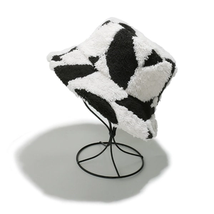 Détail d'un chapeau bob en peluche avec motif de vache noir et blanc pour l'hiver froid