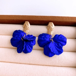Close-up of royal blue acrylic petal earrings with golden textured metal studs on velvet