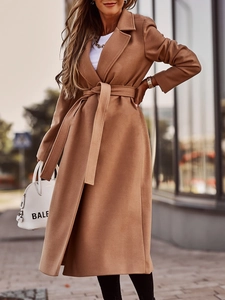 Detail of camel wool coat featuring a wide lapel design and adjustable waist belt