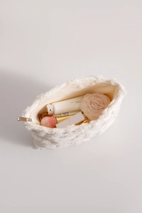 Top view of cream plush heart cosmetic bag showing interior storage and gold zipper detail