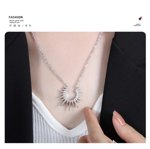Detail of silver geometric sunburst pendant necklace styled with a black suit blazer