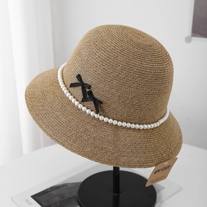 Close-up of straw sun hat with pearl chain trim and UV protection tag on display