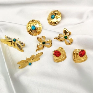Golden stainless steel earrings with colorful gemstones on white silk background