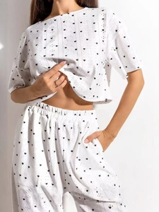 Détail d'un ensemble deux pièces blanc avec motifs coeurs noirs et maille jacquard ajourée