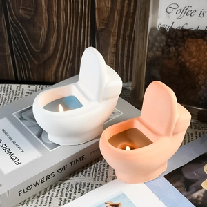 Detail shot of toilet-shaped scented candles in white and pink on decorative books