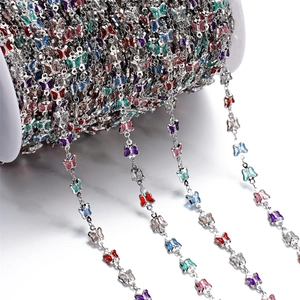 Macro detail of colorful enamel butterfly chain on a white spool for DIY jewelry making