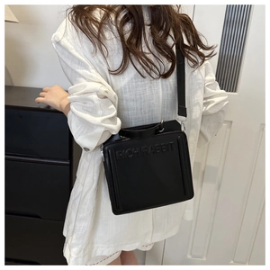 Detail of black matte leather tote bag featuring embossed Rich Rabbit logo on the surface