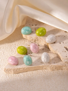 Detail of candy-colored oval titanium steel earrings with marble texture on stone