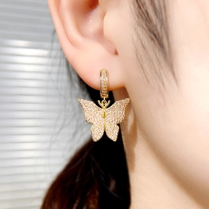 Close-up of gold butterfly hoop earrings set with sparkling pink cubic zirconia