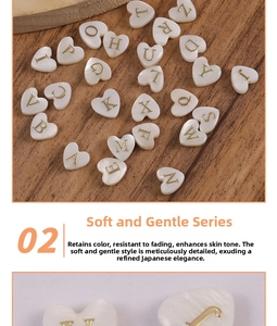Macro shot of heart-shaped shell beads with golden 3D alphabets for DIY jewelry making