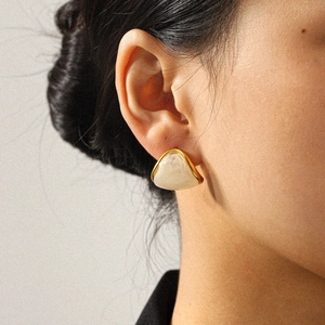 Close-up of a 18k gold-plated triangular amber resin earring worn on a model ear