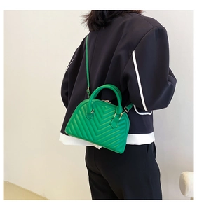 Crossbody view of a vibrant green quilted Boston bag worn with a stylish blazer