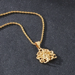 Close-up of gold Medusa pendant with twisted rope chain on black textured background