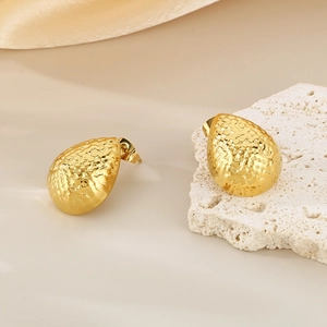 Detailed macro view of gold waterdrop earrings with a unique hammered texture finish