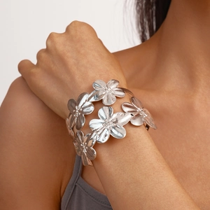 Close-up of stacked silver floral layered open cuff bracelet on a female wrist