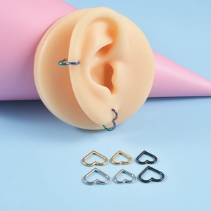 Vue macro de piercings d'oreille en forme de cœur en acier inoxydable multicolores sur modèle