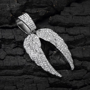 Détail du pendentif ailes d'ange argenté avec strass sur un fond texturé de charbon noir