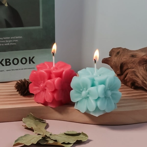 Detalle de velas florales rosas y azules con texturas de pétalos en soporte de madera