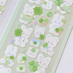 Close-up of cute white rabbit and green clover stickers with silver foil glitter detail
