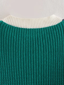 Dettaglio dello scollo in maglia a coste a contrasto su un cardigan verde operato