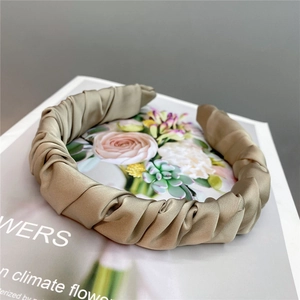 Detailed close-up of champagne satin pleated headband on a book showing fabric texture
